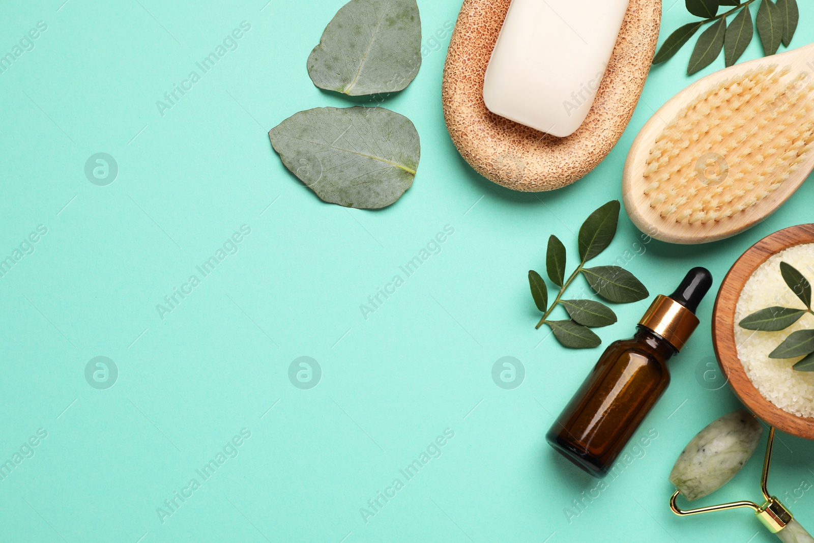 Photo of Different cosmetic products and green leaves on turquoise background, flat lay. Space for text