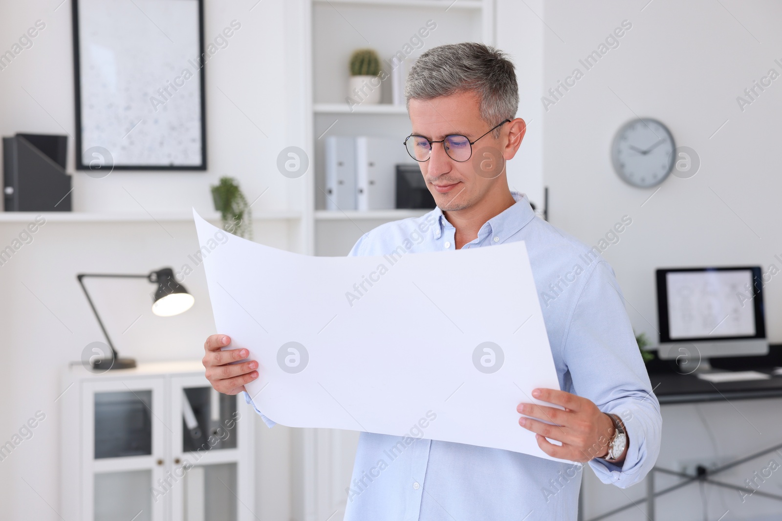 Photo of Architect holding paper sheet with engineering drawing in office