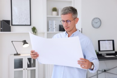 Architect holding paper sheet with engineering drawing in office