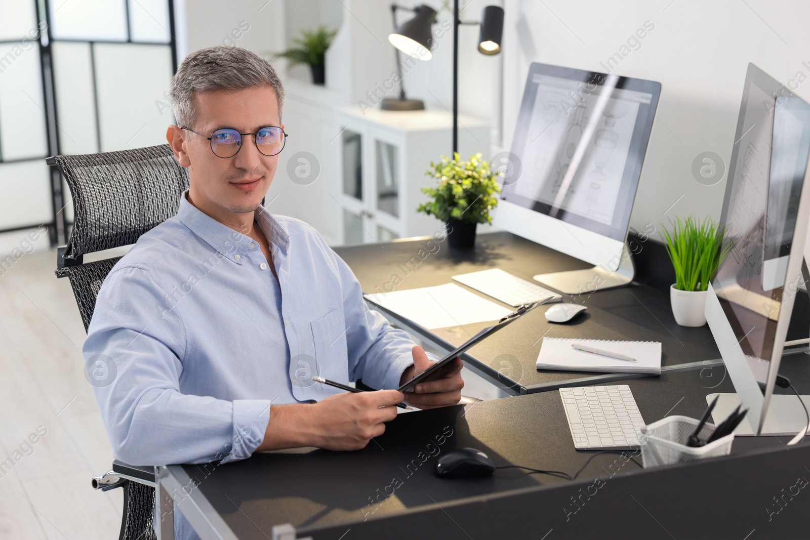 Photo of Architect checking engineering drawing at table in office