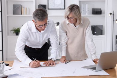 Architects making engineering drawing at wooden table in office