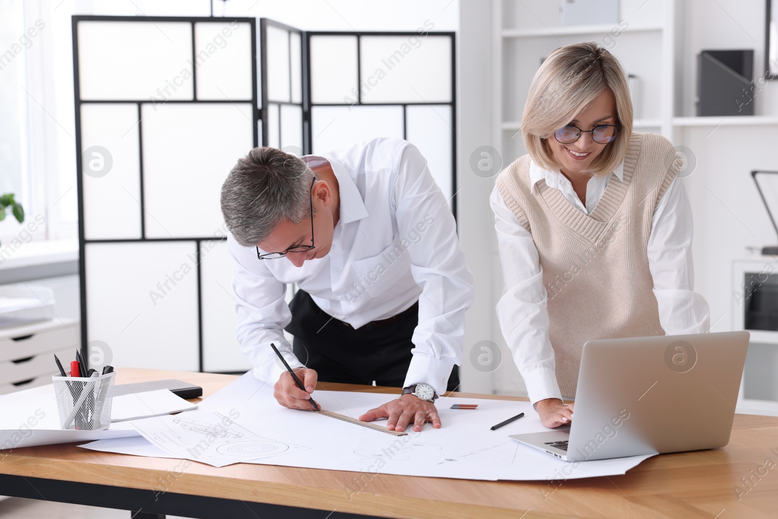 Photo of Architects making engineering drawing at wooden table in office