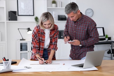 Architects making engineering drawing at wooden table in office