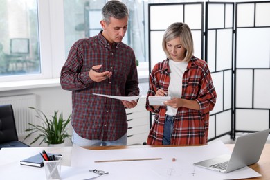 Photo of Architects discussing engineering drawing at table in office