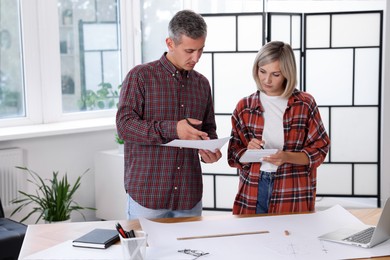 Architects discussing engineering drawing at table in office