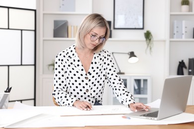 Photo of Architect making engineering drawing at table in office