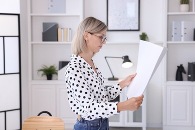 Architect holding paper sheet with engineering drawing in office