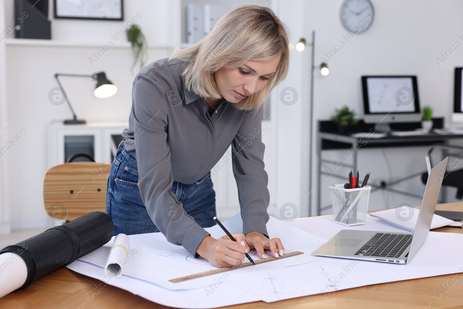 Photo of Architect making engineering drawing at wooden table in office