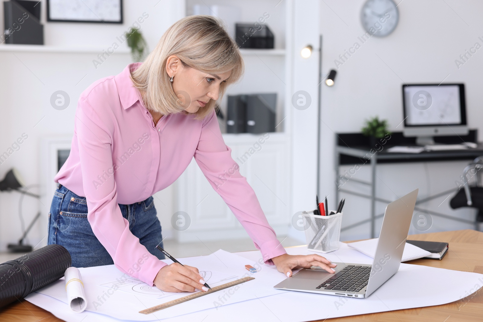 Photo of Architect making engineering drawing at wooden table in office