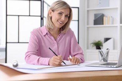 Architect making engineering drawing at table in office