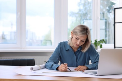 Architect making engineering drawing at table in office