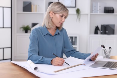 Photo of Architect making engineering drawing at table in office