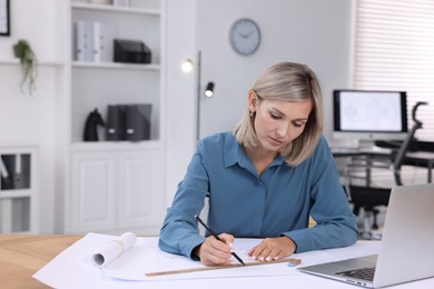 Architect making engineering drawing at table in office