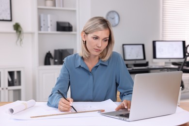 Photo of Architect making engineering drawing at table in office