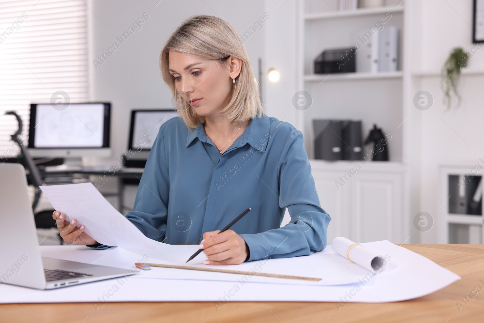 Photo of Architect making engineering drawing at wooden table in office