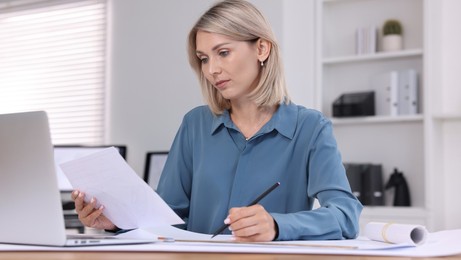 Architect making engineering drawing at table in office