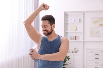 Smiling man applying spray deodorant at home