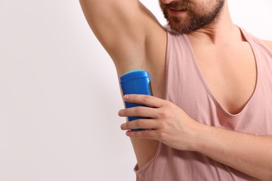 Man applying solid deodorant on white background, closeup. Space for text