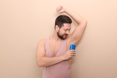 Man applying solid deodorant on beige background