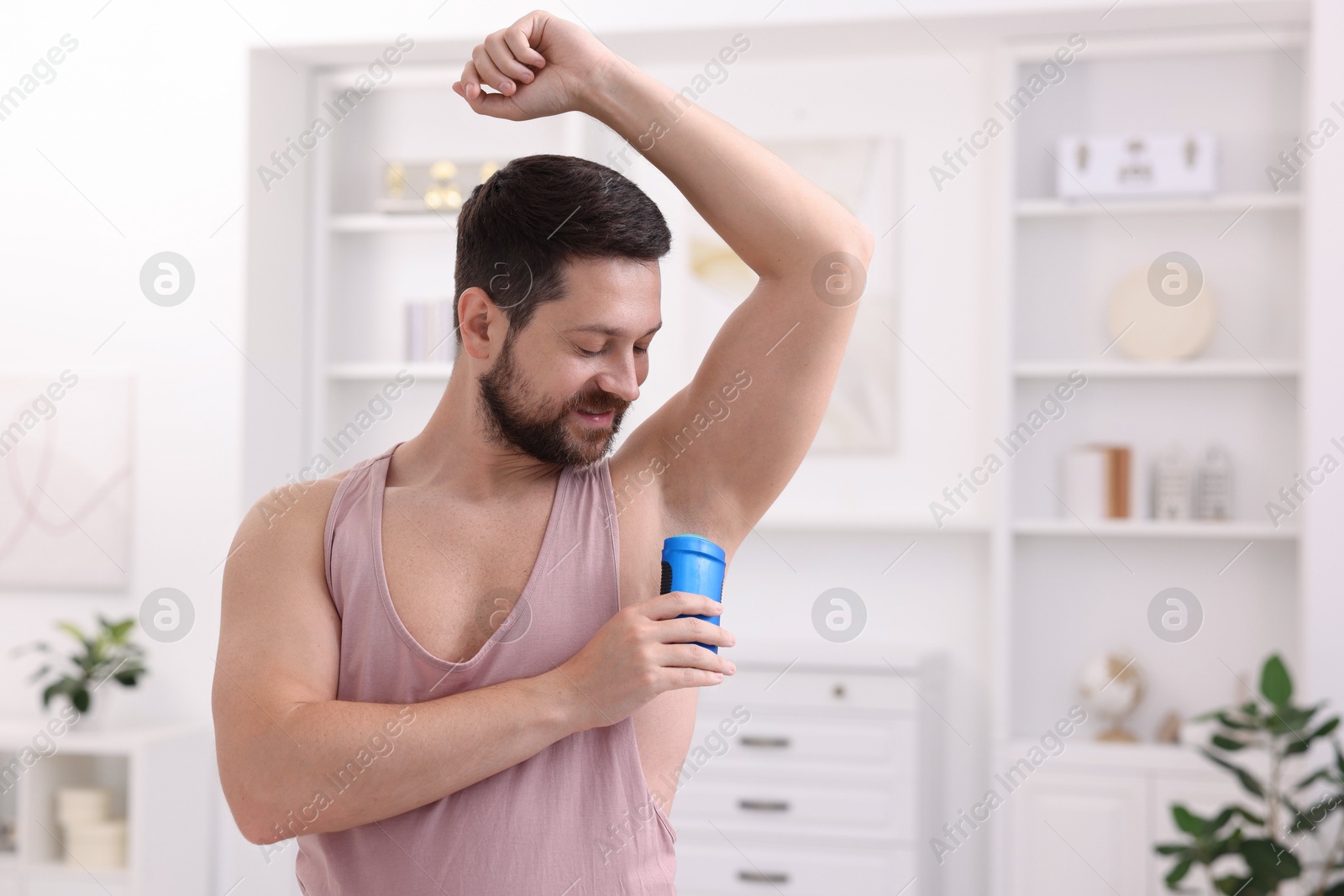 Photo of Man applying solid deodorant at home. Space for text