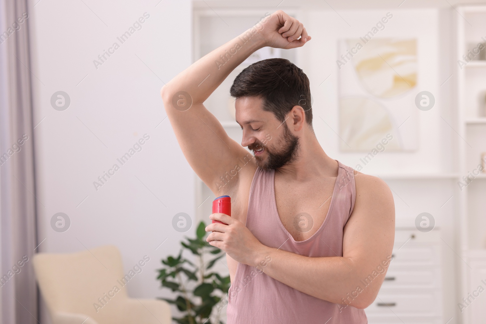 Photo of Man applying solid deodorant at home. Space for text