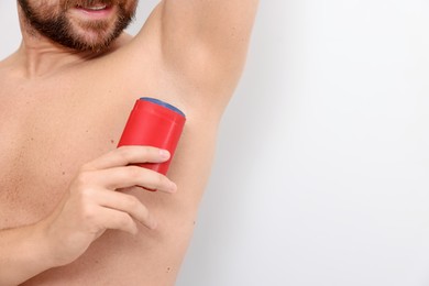 Photo of Man applying solid deodorant on white background, closeup. Space for text