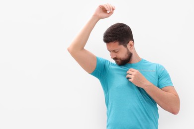 Photo of Emotional man in t-shirt before using deodorant on white background. Space for text