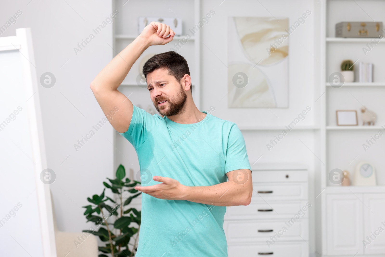 Photo of Emotional man in t-shirt before using deodorant at home