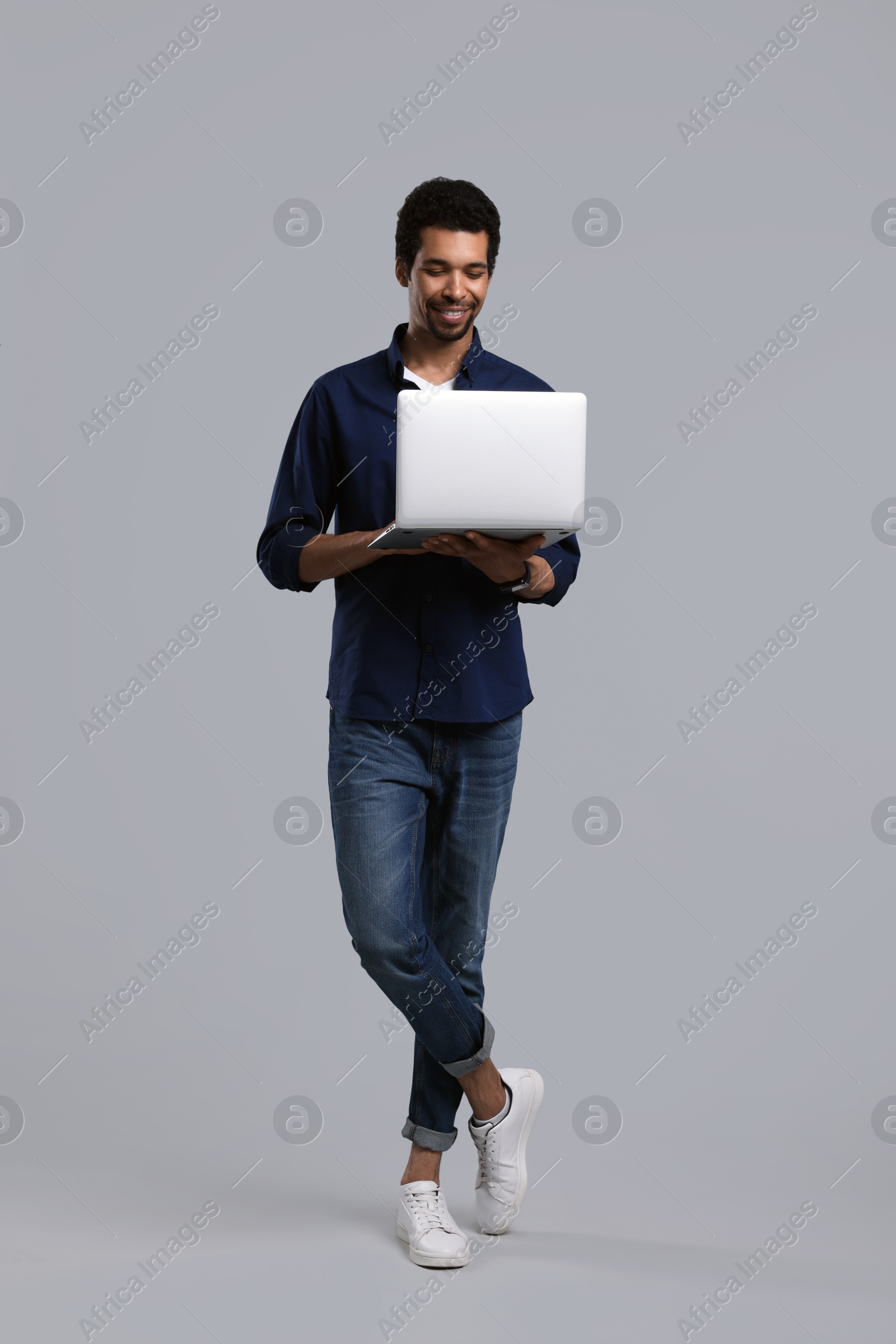 Photo of Happy man with laptop on grey background