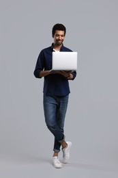 Happy man with laptop on grey background