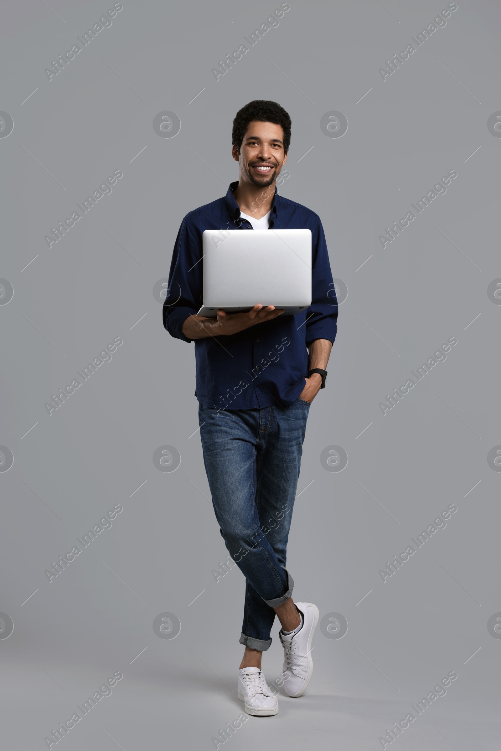 Photo of Happy man with laptop on grey background