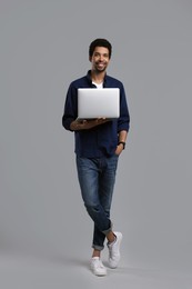 Happy man with laptop on grey background