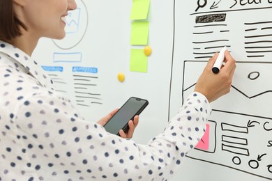 Developing UI design. Woman drawing website wireframe on whiteboard indoors, closeup