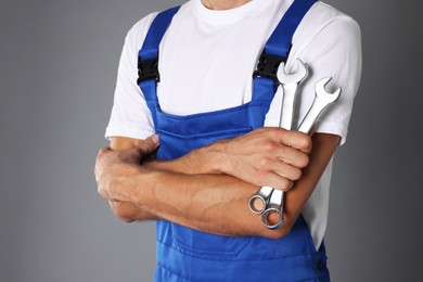 Photo of Auto mechanic with wrenches on grey background, closeup