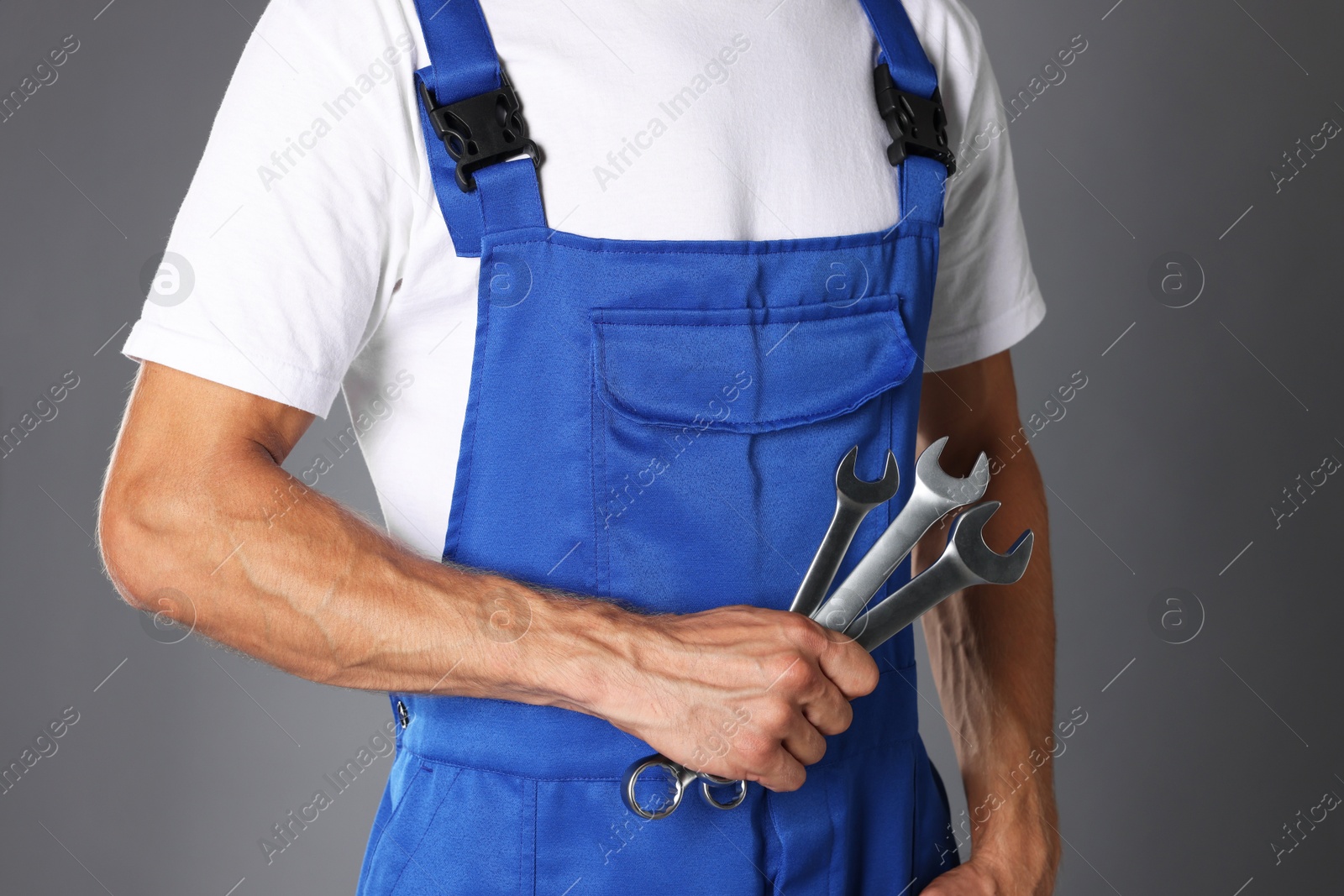 Photo of Auto mechanic with wrenches on grey background, closeup