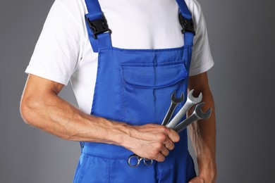 Photo of Auto mechanic with wrenches on grey background, closeup