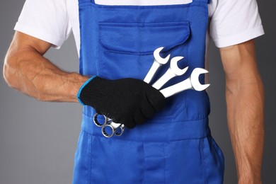 Photo of Auto mechanic with wrenches on grey background, closeup