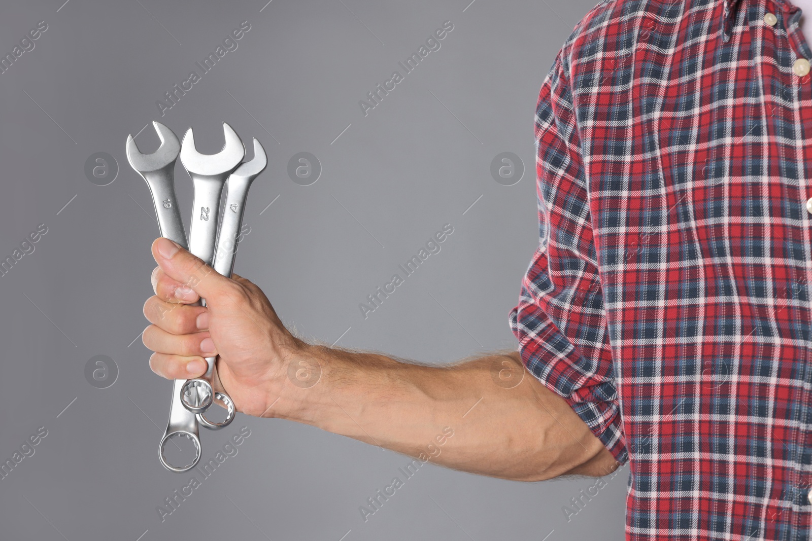 Photo of Auto mechanic with wrenches on grey background, closeup