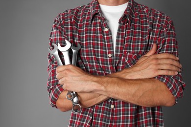 Photo of Auto mechanic with wrenches on grey background, closeup