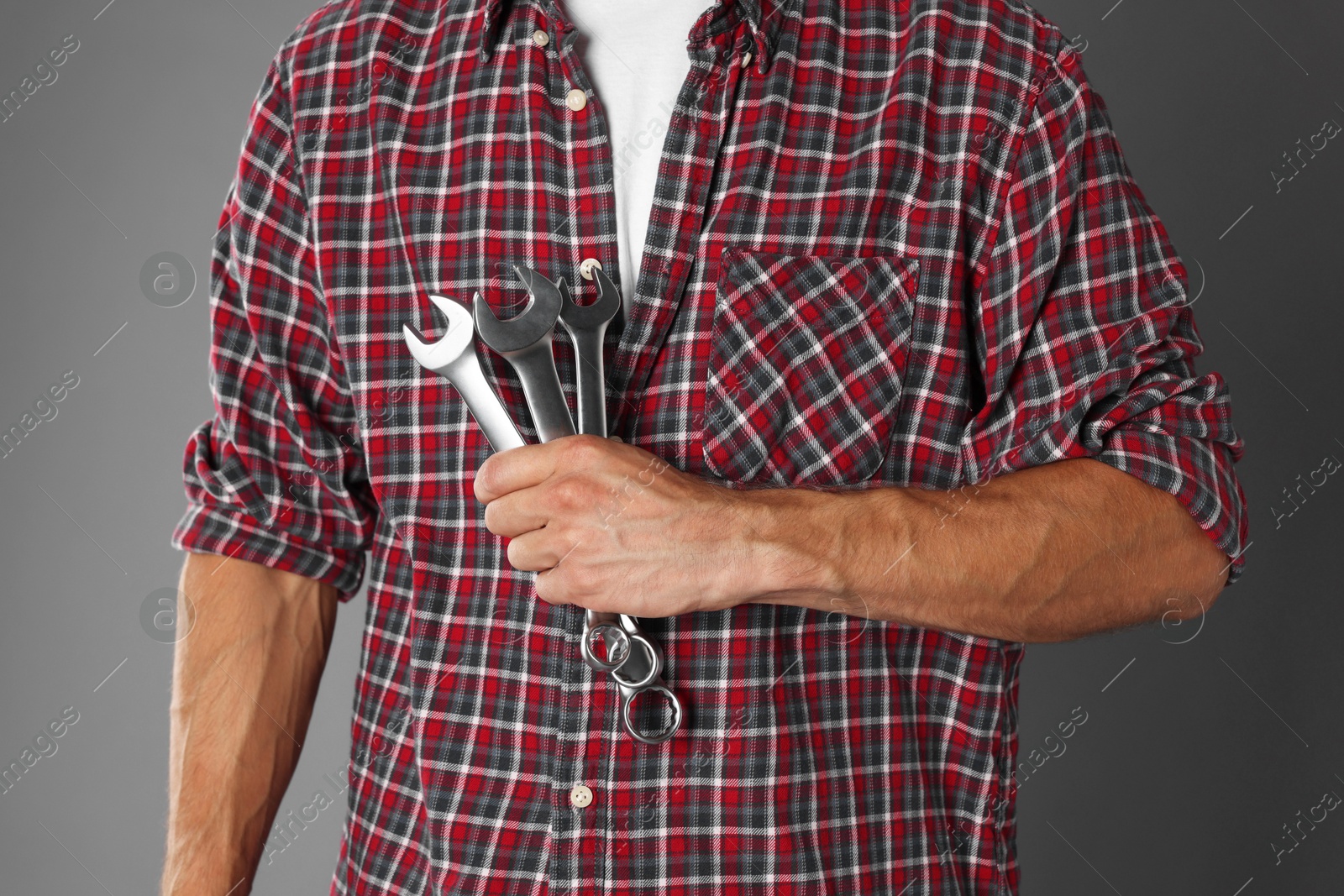 Photo of Auto mechanic with wrenches on grey background, closeup