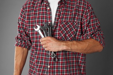 Auto mechanic with wrenches on grey background, closeup