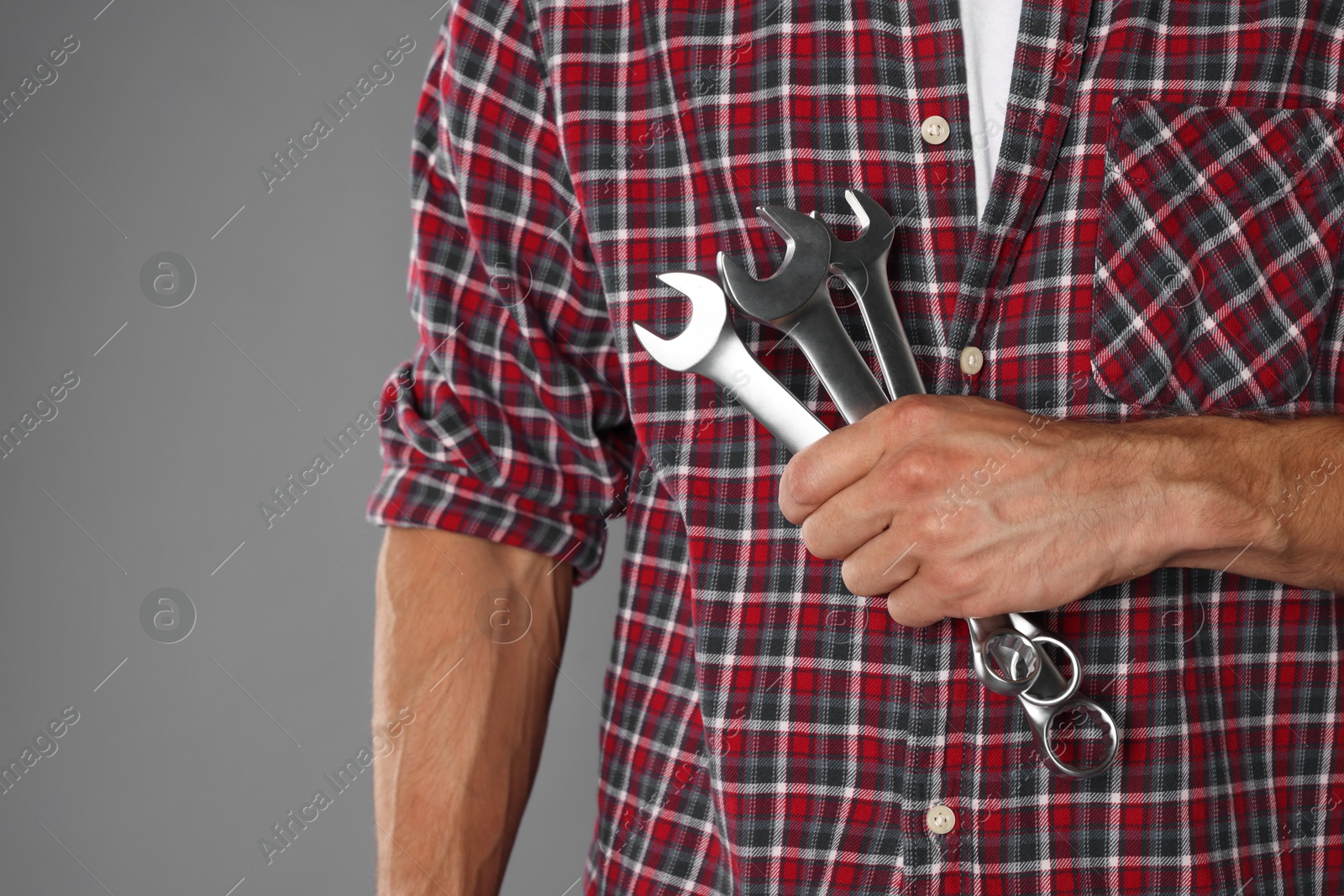 Photo of Auto mechanic with wrenches on grey background, closeup