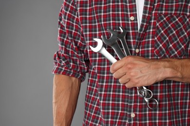 Auto mechanic with wrenches on grey background, closeup