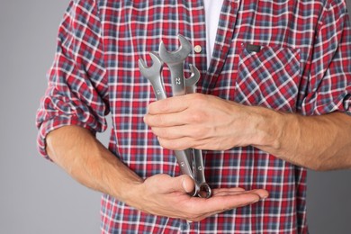 Photo of Auto mechanic with wrenches on grey background, closeup