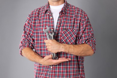 Photo of Auto mechanic with wrenches on grey background, closeup