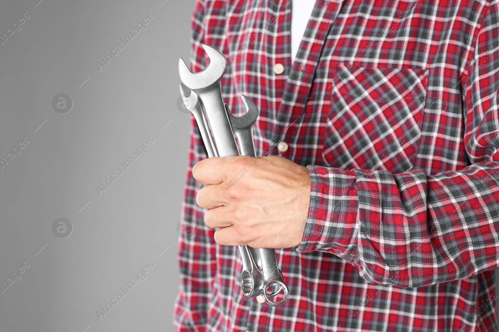 Photo of Auto mechanic with wrenches on grey background, closeup. Space for text