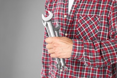 Photo of Auto mechanic with wrenches on grey background, closeup. Space for text