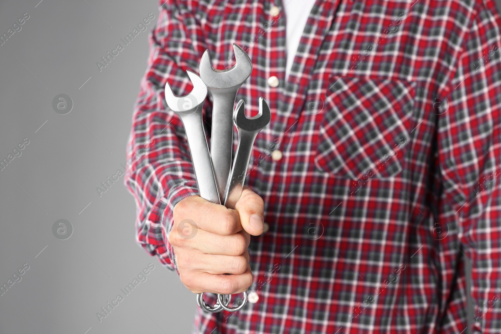 Photo of Auto mechanic with wrenches on grey background, closeup