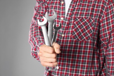 Photo of Auto mechanic with wrenches on grey background, closeup