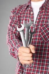 Photo of Auto mechanic with wrenches on grey background, closeup